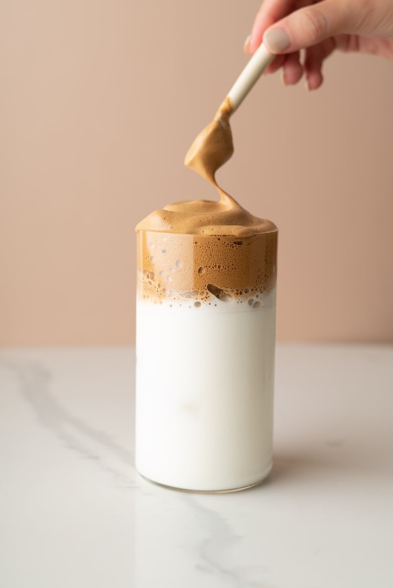 Person's Hand with Spoon Putting Coffee Froth in a Glass